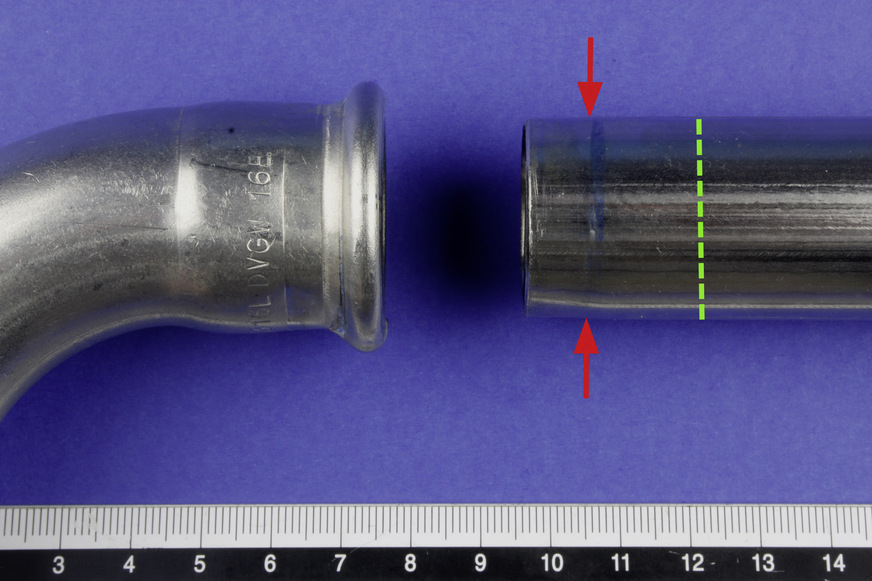 Bild 1: Die Pressverbindung hat sich gelöst. Die Pfeile markieren die tatsächliche Einschubtiefe des Rohrendes. Die grüne Markierung zeigt, wie weit das Rohrende für eine dauerhaft kraftschlüssige Verbindung in die Muffenaufnahme des Fittings hätte eingeschoben werden müssen