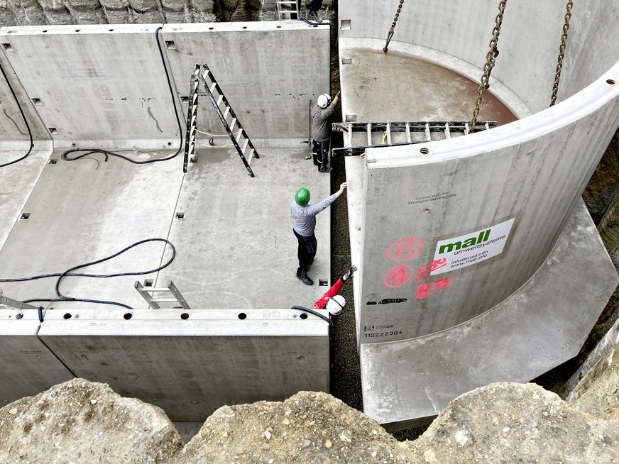 Thermischer Pufferspeicher. Montage eines runden Endstücks mit Überstand der Bodenplatte als Auftriebssicherung. Die Auflast nach Verfüllen der Baugrube wirkt dem Auftrieb des leeren Behälters bei hohem Grundwasserstand entgegen.