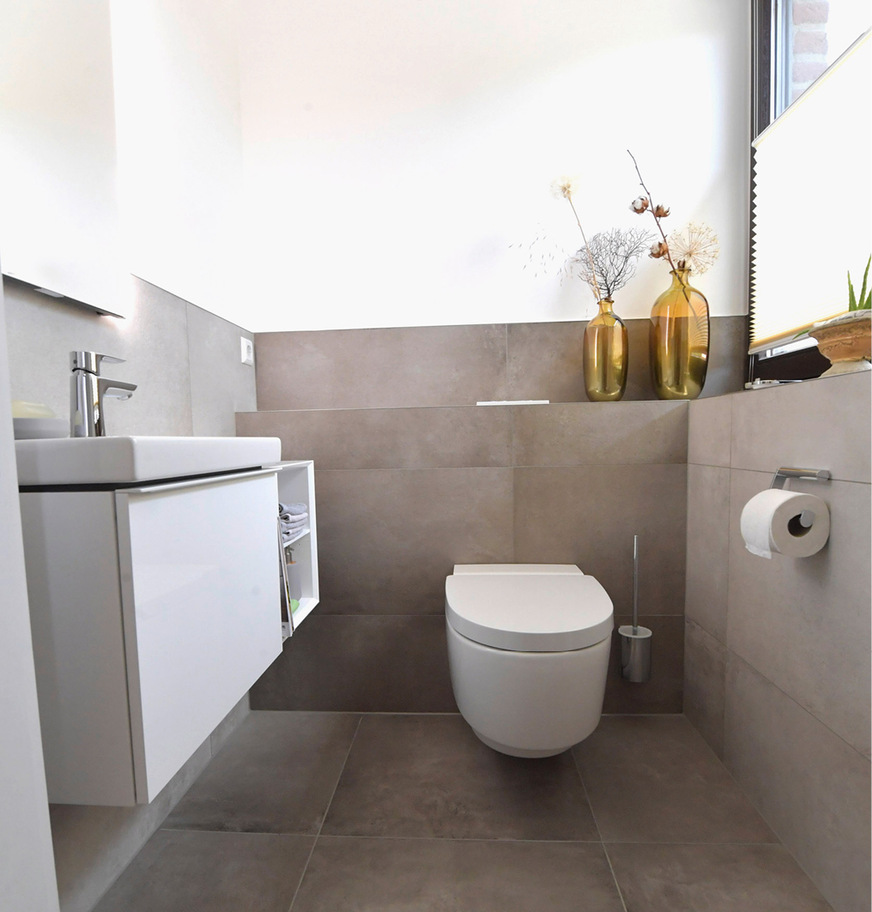 Durch die schlichten, großformatigen Fliesen und die hellen Badmöbel wirkt das neue Gästebad deutlich geräumiger.