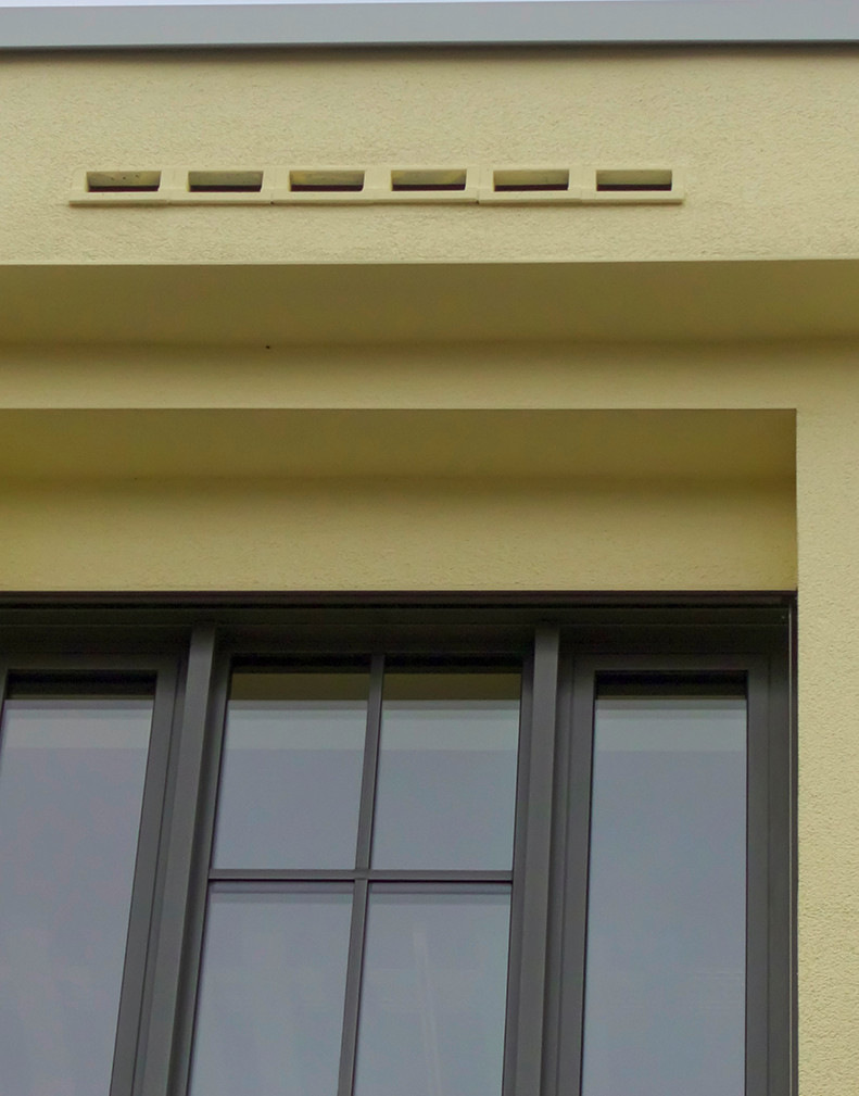 Einflugschlitze für Fledermäuse in der Attika des Dachvorsprungs. Die Fledermauskästen ­wurden im Zuge der Gebäudemodernisierung in die denkmalgeschützte Fassade integriert.