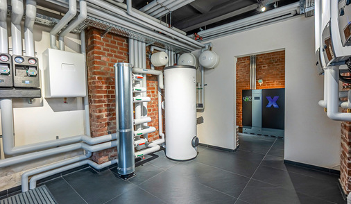 Blick in den neu gestalteten Heizungsraum: Die Inneneinheiten der Wärmepumpen sowie der Brauchwasserspeicher sind übersichtlich und technisch klar strukturiert installiert.