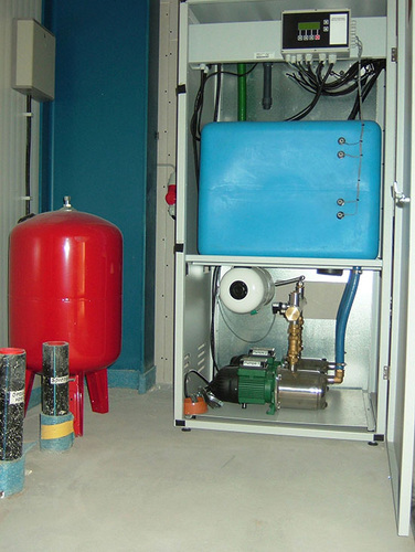 Komplettsystem Druckerhöhungsanlage Tano XL mit integrierter 
Trinkwassernachspeisung, Vorlagebehälter 200 l (blau), 
Druckausgleichsbehälter 100 l (rot) und Zubringerpumpe mit Zubehör im 
unterirdischen Betonfertigteilspeicher
(Bild: Mall)