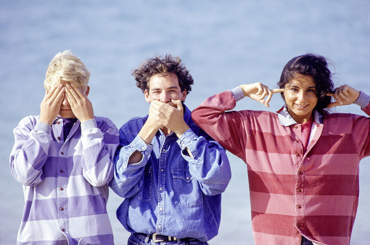 Three young friends making gestures at ocean, portrait