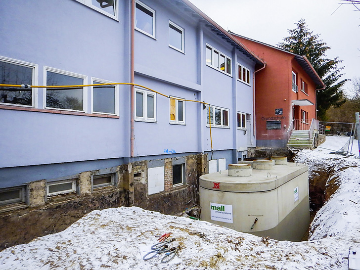 Einbau des neuen Pelletspeichers unter beengten Verhältnissen auf der Nordseite. Der Fertigteil-Ovalbehälter wurde per Autokran direkt vom Lieferfahrzeug an die Stelle des früheren Öltanks gesetzt. 