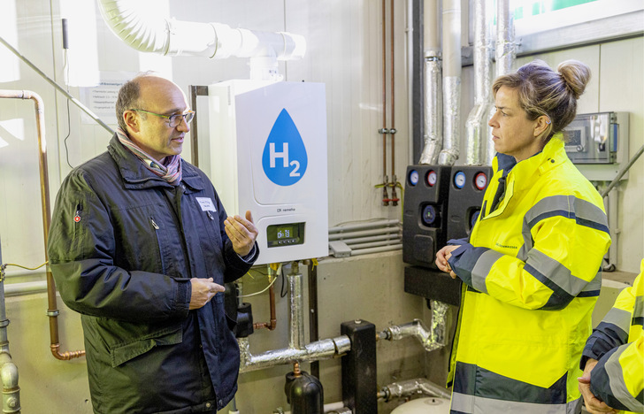 NRW-Wirtschaftsministerin Mona Neubaur im Gespräch mit Remeha-Vertriebsleiter Franz Killinger vor dem 100 % Wasserstoff-Brennwertkessel von Remeha. 