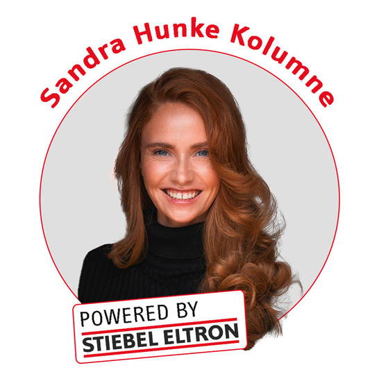 Lächelnde Frau mit langen roten Haaren, Text: "Sandra Hunke Kolumne, Powered by Stiebel Eltron".
