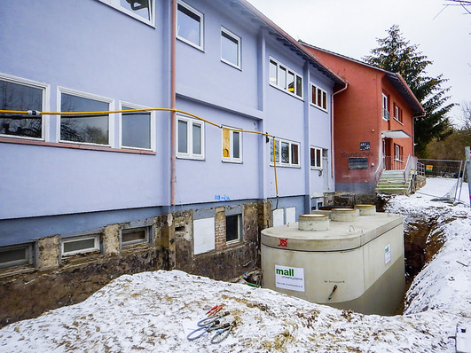 Einbau des neuen Pelletspeichers unter beengten Verhältnissen auf der Nordseite. Der Fertigteil-Ovalbehälter wurde per Autokran direkt vom Lieferfahrzeug an die Stelle des früheren Öltanks gesetzt. 