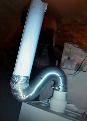 Detailaufnahme eines installierten Metall-Lüftungssystems in einem Technikraum, das an eine zentrale Heizungsanlage angeschlossen ist, verdeutlicht die Verbindungselemente und die fachgerechte Montage.